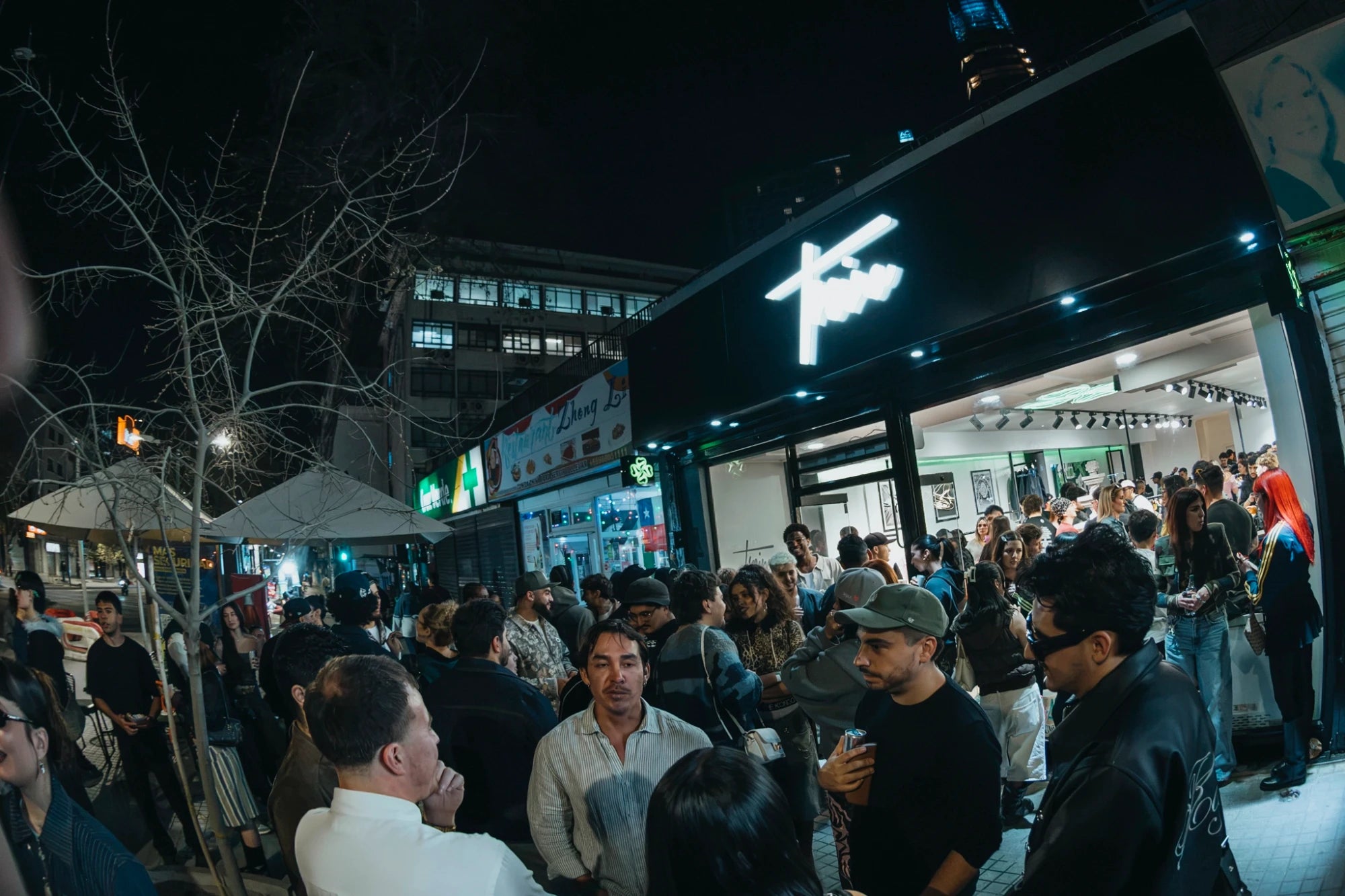 Fachada de noche de la tienda Treino en Av. Providencia 2510, Santiago, con su comunidad afuera