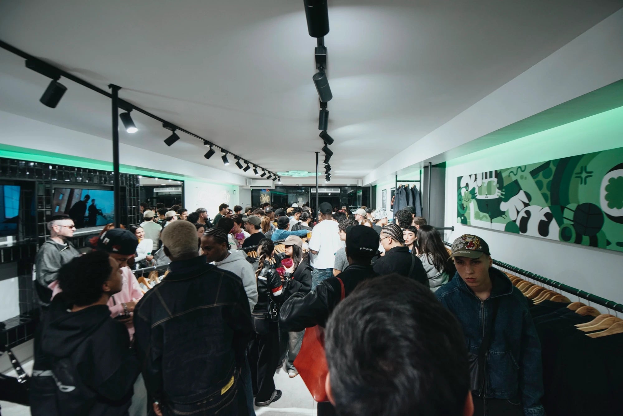 Interior de la tienda Treino en Providencia durante su inauguración, con mural verde y percheros de ropa urbana
